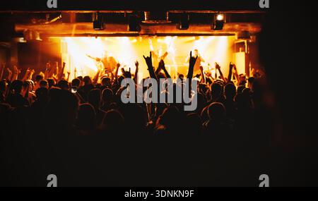 Das Publikum jubelte bei einem Live-Konzert mit hellen Bühnenlichtern, die die Darsteller beleuchten. Stockfoto