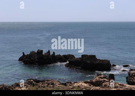 Scharfe vulkanische Felsformationen im Atlantik, Cascais Küste, Portugal. Stockfoto