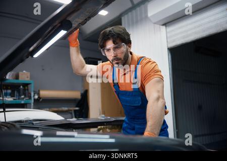 Automechaniker inspiziert den Motor unter der Motorhaube in der Garage Stockfoto