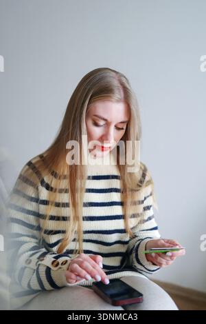 Attraktive blonde Frau mit Kreditkarte, die bargeldloses Bezahlen und E-Commerce fördert Stockfoto