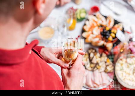 Ein Mann steht bei einem festlichen Abendessen und hält ein Glas Champagner. Stockfoto