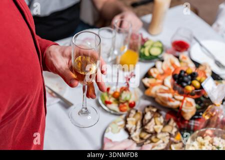 Ein Mann steht bei einem festlichen Abendessen und hält ein Glas Champagner. Stockfoto