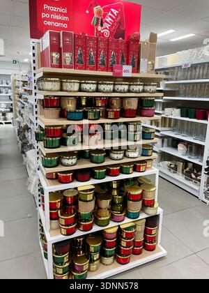 Gestapelte Weihnachtskerzen in dekorativen Gläsern auf einem Ladenstand mit festlicher Beschilderung und Verpackung. PEPCO-Speicher. Belgrad, Serbien 3. Dezember 2025 Stockfoto