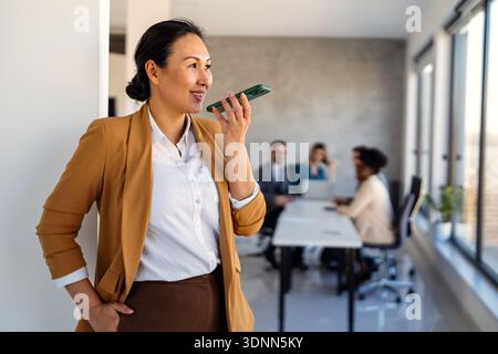 Lächelnde erfolgreiche Geschäftsfrau, freiberufliche Mitarbeiterin, weibliche Führungskraft mit digitalem Gerät, Telefon Stockfoto