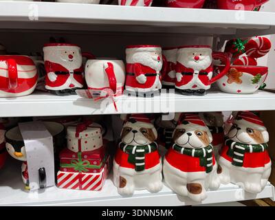 Keramikbecher in Form von Weihnachtsmann, Schneemännern und Hunden in den Regalen des Ladens. Konzept festlicher Wärme und saisonaler Geschenke Stockfoto
