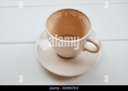 Leere Kaffeetasse auf einem weißen Tisch nach dem Trinken. Minimale Lebensstil-Szene, die Pause, Routine, beendete Pause und ruhigen Alltagsmoment symbolisiert. Stockfoto