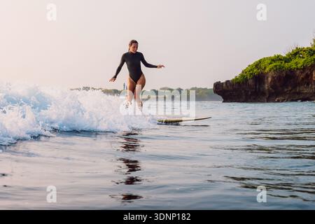 Surferfrau auf Surfbrettfahrten auf kleiner Schaumwelle auf Bali. Stockfoto
