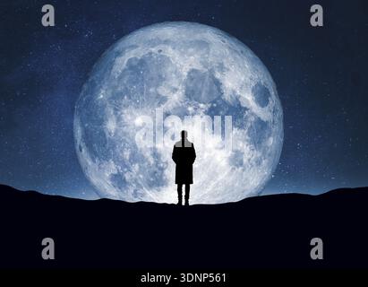 Eine einsame menschliche Figur steht unter einem leuchtenden Vollmond, umgeben von dem weitläufigen Universum, und fängt das Wesen des Wunders und des M ein Stockfoto