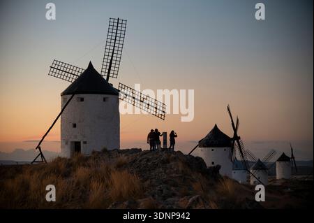 Silhouetten bei Sonnenuntergang zwischen den Windmühlen von La Mancha, Spanien Stockfoto