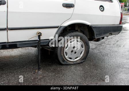Ein altes Auto auf der Straße mit einem beschädigten Reifenpannen. Details zum Reifenwechsel. Stockfoto
