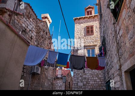 Kleidung trocknet auf einer Linie zwischen Steinhäusern in einer schmalen Allee von Dubrovnik - Dubrovnik, Kroatien Stockfoto