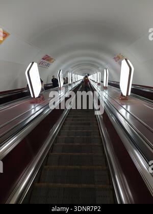 Das Innere der U-Bahn-Station Kiew zeigt einen langen Rolltreppentunnel, der die Passagiere zwischen den unterirdischen Bahnsteigen und den darüberliegenden Straßen der Stadt befördert. Kiew Stockfoto