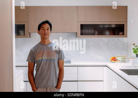 Asiatischer Mann, der in seiner Küche steht Stockfoto