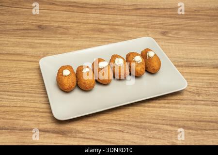 Eine große Platte mit blassorangen Kürbis- und Walnusskroketten, mit Walnussteilen in der Beschichtung – perfekt für den Herbst. Stockfoto