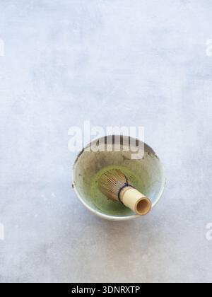 Matcha grüner Tee mit Bambusbesen in einer Keramikschale auf Betonhintergrund Stockfoto