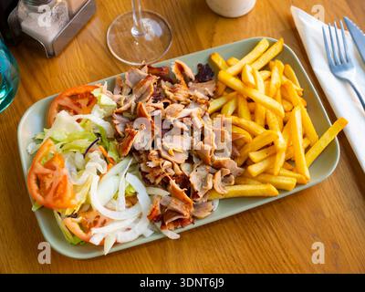 Gericht mit appetitanregenden Beilagen armenischer Küche mit köstlichem Shish Kebab, pommes frites, gebackenem Gemüse, Tomaten Stockfoto