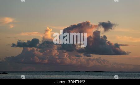 Weiche pastellfarbene Wolken ziehen bei Sonnenuntergang in Moorea über dem ruhigen Ozean Stockfoto
