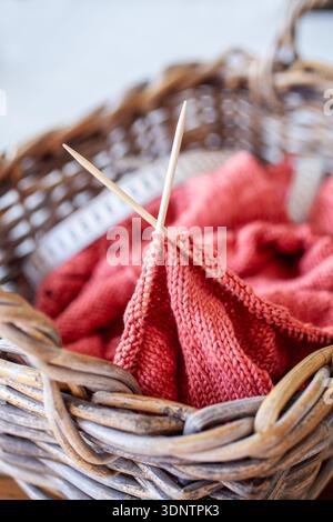 Nahaufnahme eines Strickprojekts in einem Korb mit weichen Garn-Holznadeln und einem Maßband die Szene zeigt handgefertigte Werkstoffe und Stockfoto