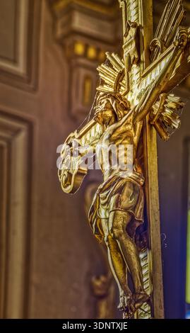 Das Sonnenlicht erleuchtet ein goldenes Kruzifix im Vollschuss. Das Kruzifix befindet sich ​​placed in der Mitte des vertikalen Rahmens, der Blickpunkt ist jedoch vom bot aus Stockfoto