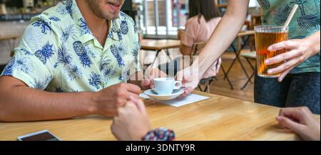 Banner einer anonymen Kellnerin, die jungen glücklichen Paaren Kaffee am Kaffeetisch serviert Stockfoto