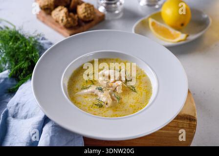 Traditionelle griechische Hähnchensuppe mit Zitrone und Gemüse in rustikalem Restaurant. Stockfoto