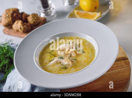 Traditionelle griechische Hähnchensuppe mit Zitrone und Gemüse in rustikalem Restaurant. Stockfoto