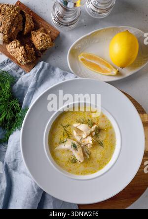 Traditionelle griechische Hähnchensuppe mit Zitrone und Gemüse in rustikalem Restaurant. Stockfoto