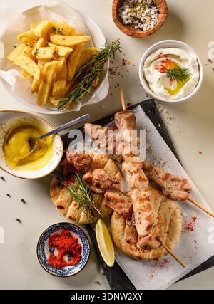 Gegrillte Hähnchensovlaki-Spieße, die auf einem rustikalen Restauranttisch als traditionelles griechisches Gericht serviert werden. Stockfoto