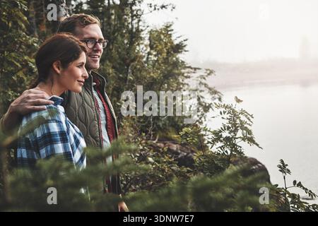 Wandern, Umarmen und Landschaft mit Paar in den Bergen zusammen für Abenteuer, Hobby oder Wildnis Aktivitäten. Bindung, Liebe und Sichtweise mit Menschen, die sich umarmen Stockfoto