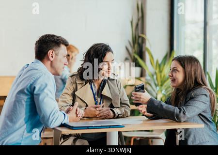 Kollegen diskutieren Smartphone-Inhalte während der Büropause Stockfoto