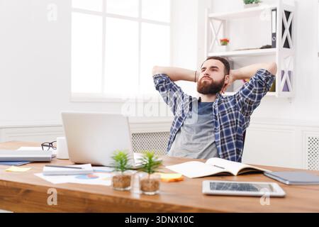 Junger, entspannter Mann mit Laptop im modernen weißen Büro Stockfoto