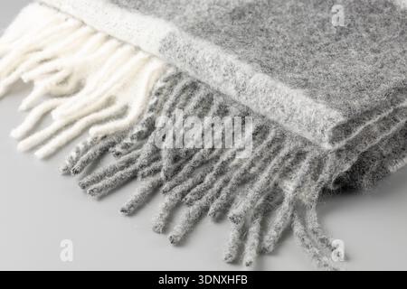 Weicher, warmer Schal aus Alpakawolle im Blockfarben-Stil. Gefalteter trendiger, cremegrauer Schal auf neutralem Hintergrund. Stockfoto