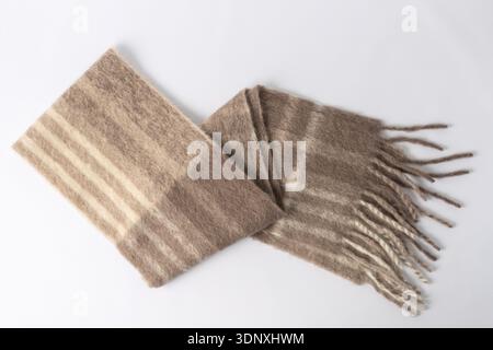 Weicher, warmer Schal aus Alpakawolle im Blockfarben-Stil. Gefaltetes trendiges cremebraunes Tuch auf neutralem Hintergrund. Stockfoto
