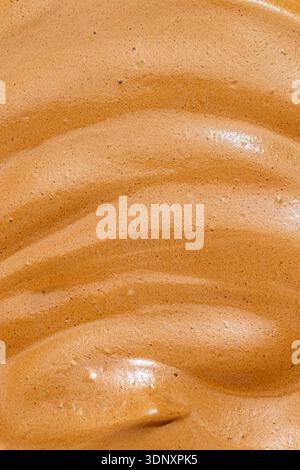 Nahaufnahme von cremigem Milchkaffee, der die glatte und strukturierte Oberfläche hervorhebt. Ideal für Kaffeeliebhaber, die reichhaltiges entdecken möchten Stockfoto