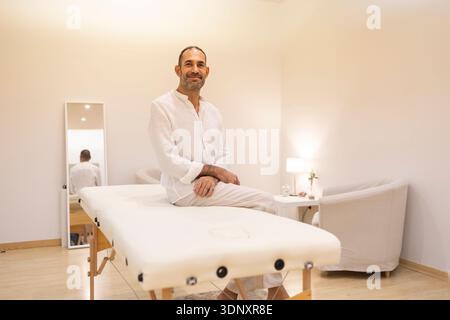 Ein Psychologe sitzt auf einem Massagetisch in einer ruhigen psychologischen Klinik und schafft eine einladende und komfortable Umgebung für Therapie und psychische Gesundheit Stockfoto