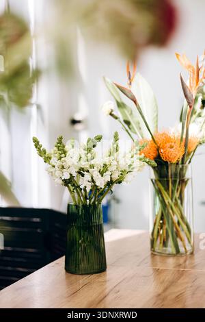 Ein wunderschöner Blumenstrauß in einem Blumenladen. Das Arrangement zeigt leuchtende Blüten in Glasvasen, die eine elegante und farbenfrohe Atmosphäre schaffen Stockfoto