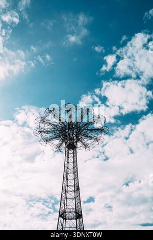 Faszinierender Blick auf den Fallschirmsprung, eine ikonische Stahlkonstruktion in Coney Island, New York City, vor einem leuchtend blauen Himmel mit verstreuten Wolken Stockfoto