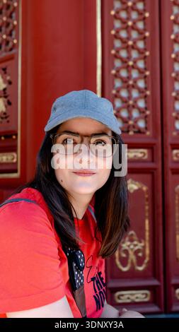 Eine Frau in lässiger Kleidung genießt einen sonnigen Tag im Jingshan Park, Peking, China, mit traditionellen architektonischen Details, die eine wunderschöne Kulisse bilden Stockfoto