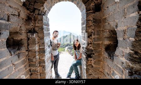 Ein Paar genießt einen atemberaubenden Blick auf den restaurierten Abschnitt Jinshanling der Chinesischen Mauer, ein beliebtes Touristenziel in Peking, das für mich bekannt ist Stockfoto