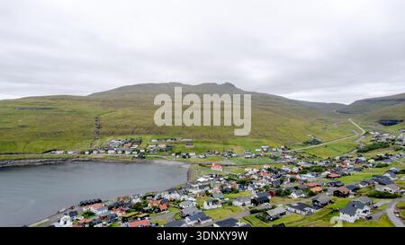 Ein atemberaubender Blick auf Sandavagur mit seiner berühmten weißen Kirche mit einem roten Dach. Eingebettet auf der Insel Vagar und den Färöern, verschmilzt die Landschaft Natur Stockfoto