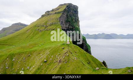 Eine atemberaubende Landschaft des Leuchtturms von Kallur auf den grünen Klippen von Kalsoy, Färöer Inseln. Die Szene zeigt die dramatische Mischung aus robustem Co Stockfoto
