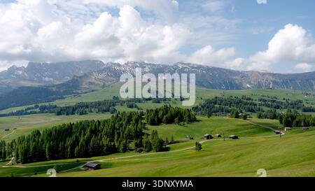 Ein atemberaubender Blick auf die Seiser Alm, die Seiser Alm in den Dolomiten, Italien, mit üppig grünen Wiesen, verstreuten Holzhütten und einem majestätischen Berg Stockfoto