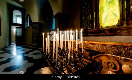 Stimmungsvoller Blick auf einen Altar mit Kerzenlicht in einer historischen Kirche in Como, Italien. Das warme Leuchten der Kerzen beleuchtet das Innere des Steins und schafft einen Stockfoto