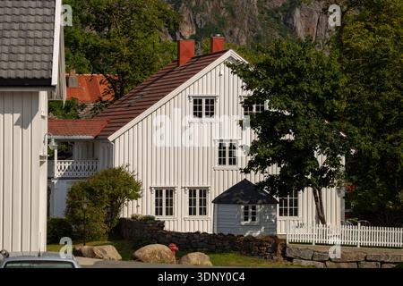 Ein malerisches weißes Haus, eingebettet in üppiges Grün auf den malerischen Lofoten-Inseln, Norwegen, mit traditioneller Architektur inmitten natürlicher Schönheit. Stockfoto