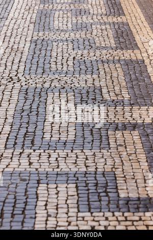 Nahaufnahme eines traditionellen portugiesischen Calcada-Gehwegs in Lissabon, der die komplizierten schwarz-weißen Mosaikmuster zeigt, die typisch für Viertel wie Ba sind Stockfoto