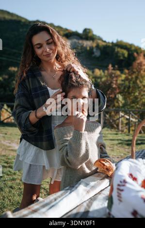 Ein ruhiges Familien-Picknick entfaltet sich in der atemberaubenden italienischen Landschaft, wo Mutter und Tochter eine gute Zeit zusammen genießen, inmitten üppigen Grüns und Fre Stockfoto