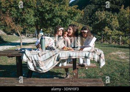 Eine fröhliche Familie genießt ein ruhiges Picknick in der üppigen italienischen Landschaft. Die Szene fängt Lachen und gemeinsame Momente inmitten der Schönheit der Natur ein Stockfoto