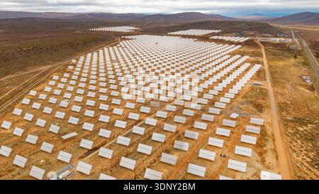 Aus der Vogelperspektive erblicken Reihen von Solarpaneelen, die unter dem Himmel leuchten und die riesige Energielandschaft widerspiegeln, die sich über das trockene Gelände, Touws River, Wes, erstreckt Stockfoto