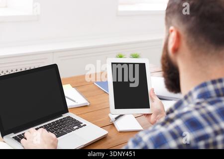Junger Manager, der im Büro mit Laptop und Tablet arbeitet, Nahaufnahme Stockfoto