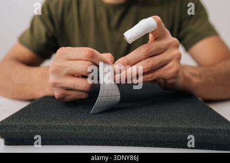 Männliche Hände halten Kinesiologiebänder, die Unterstützung und Schmerzlinderung bei Muskelverletzungen oder Gelenkproblemen bieten, Sportmedizin und Stockfoto